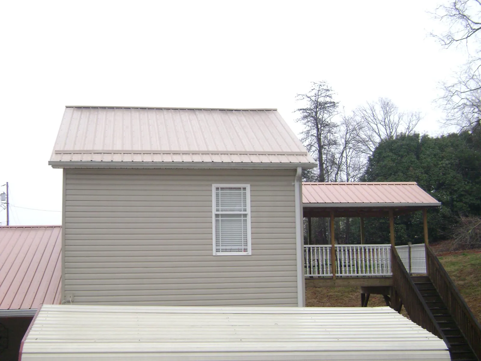 Tan metal roofs on a two story addition and attached porch, from a Roof Replacement job in Watkins